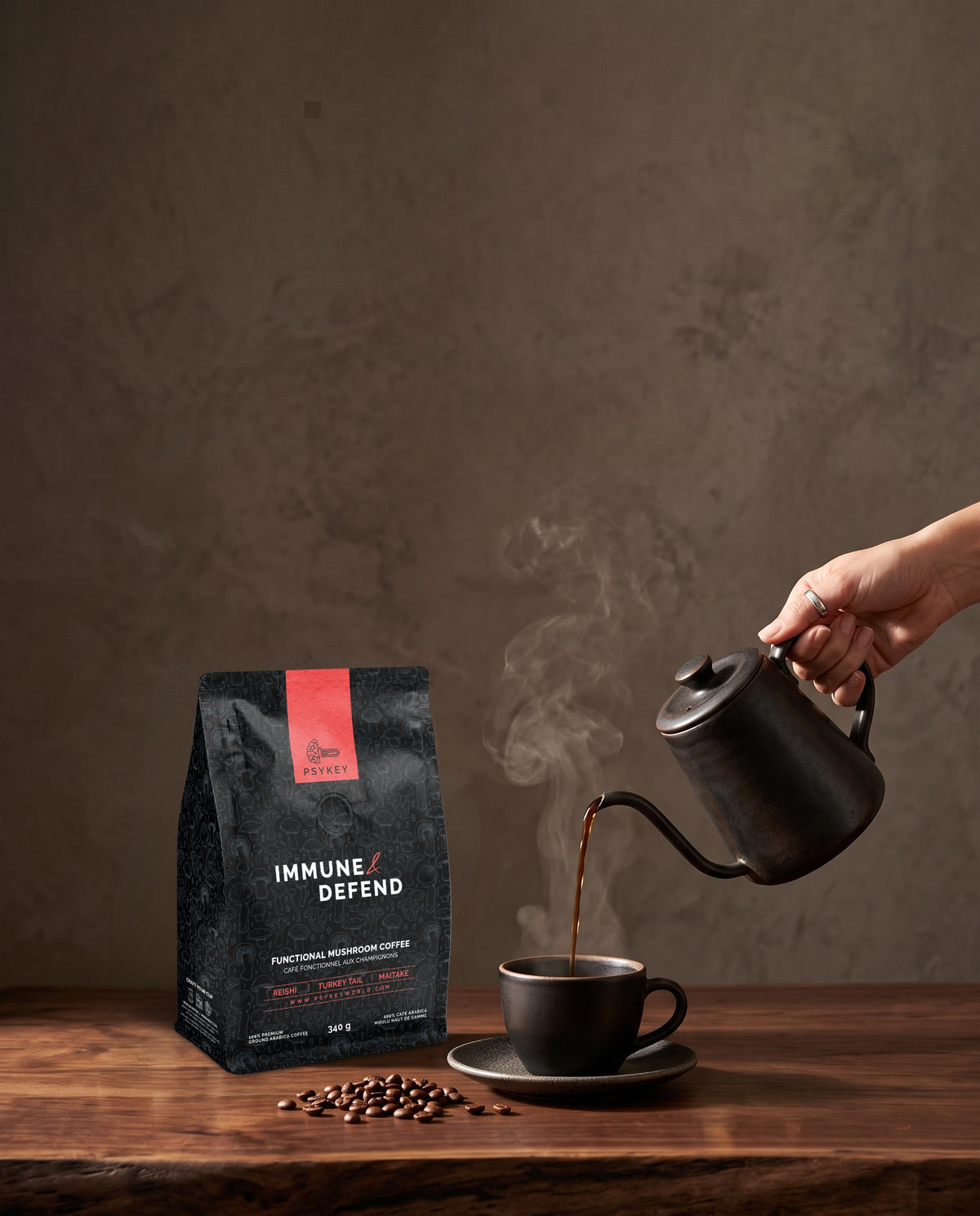 PsyKey coffee bag placed on a table with coffee beans scattered around it, while a hand pours coffee from a kettle into a mug.